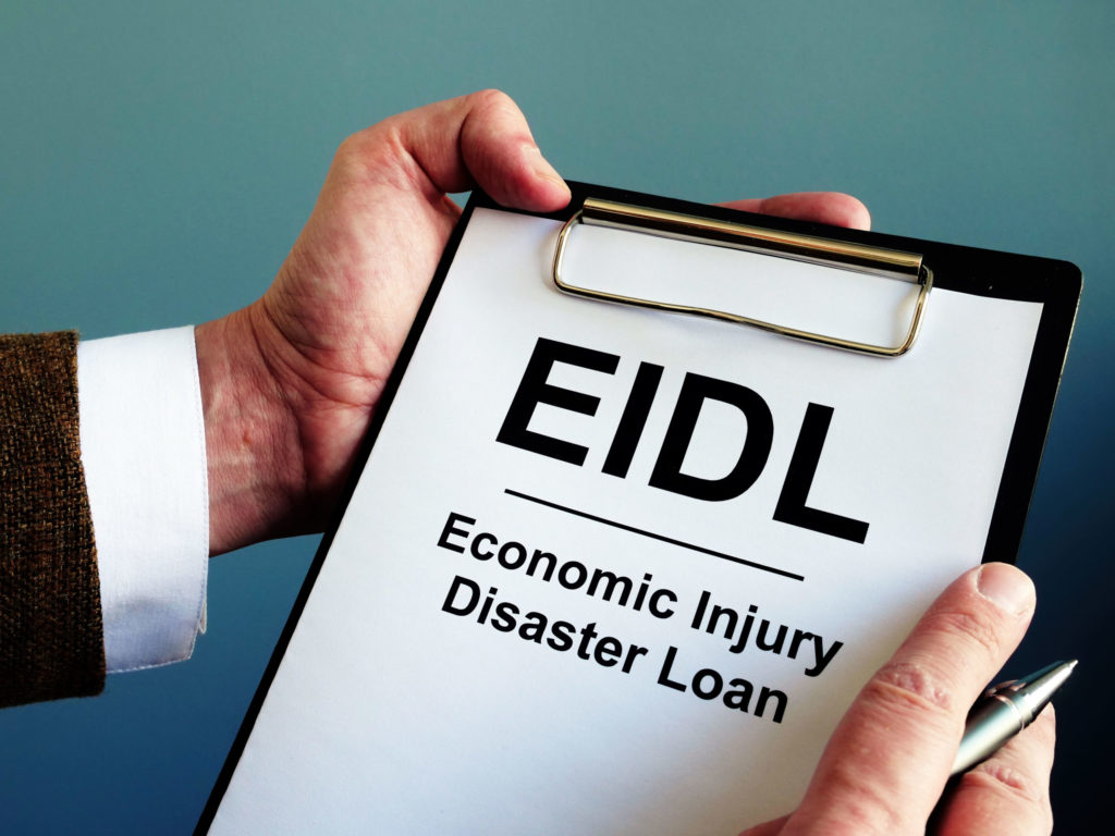 person holding clipboard with cover sheet that reads: "EIDL Economic Injury Disaster Loan"